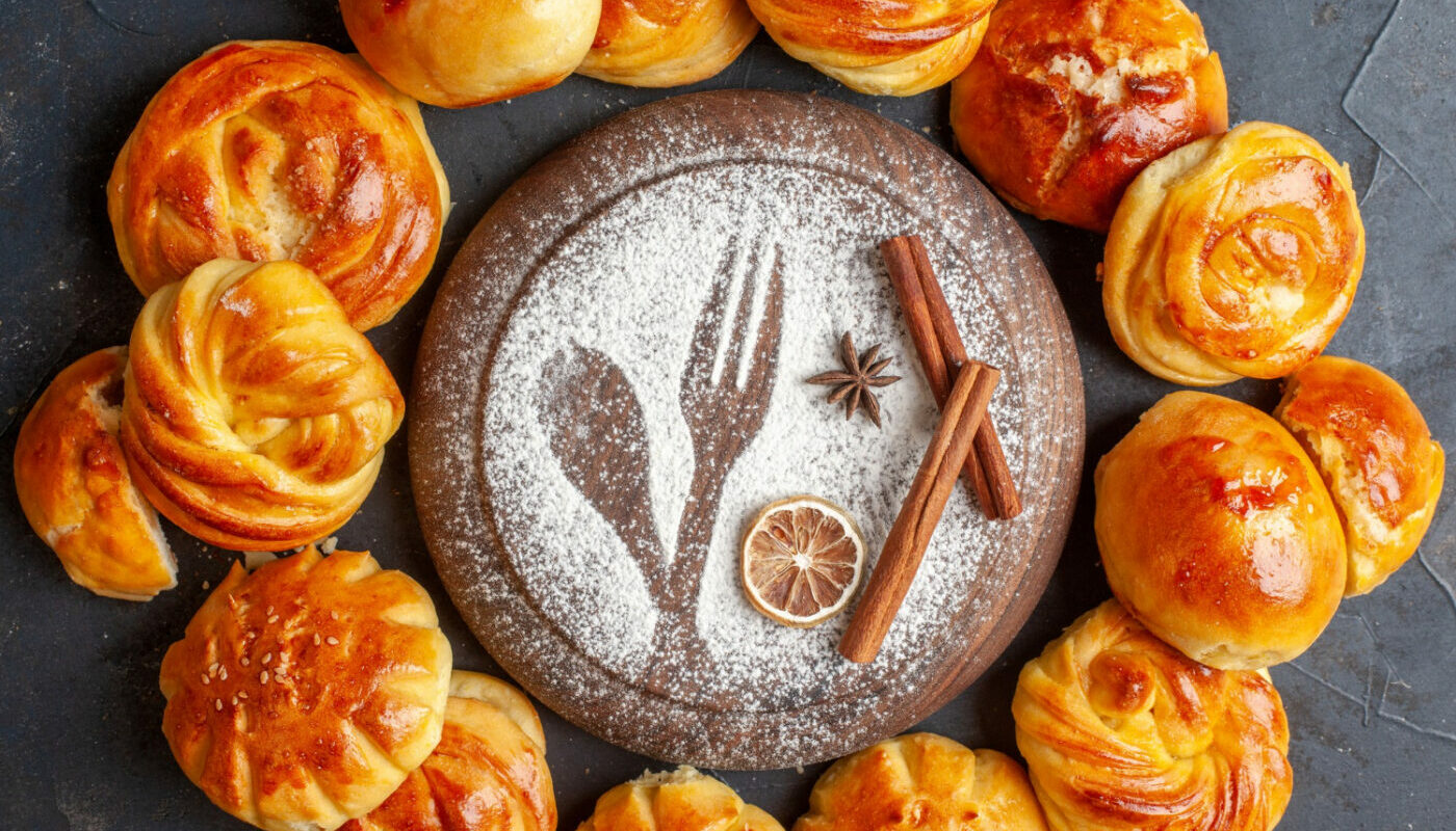 Булочки лежат на столе вокруг деревянной доски