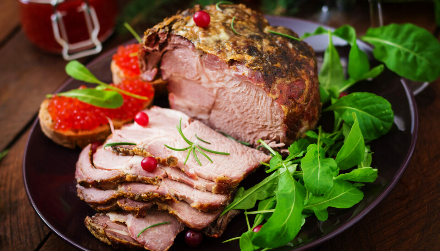 Сочная буженина на блюде в окружении зелени и бутербродов с икрой