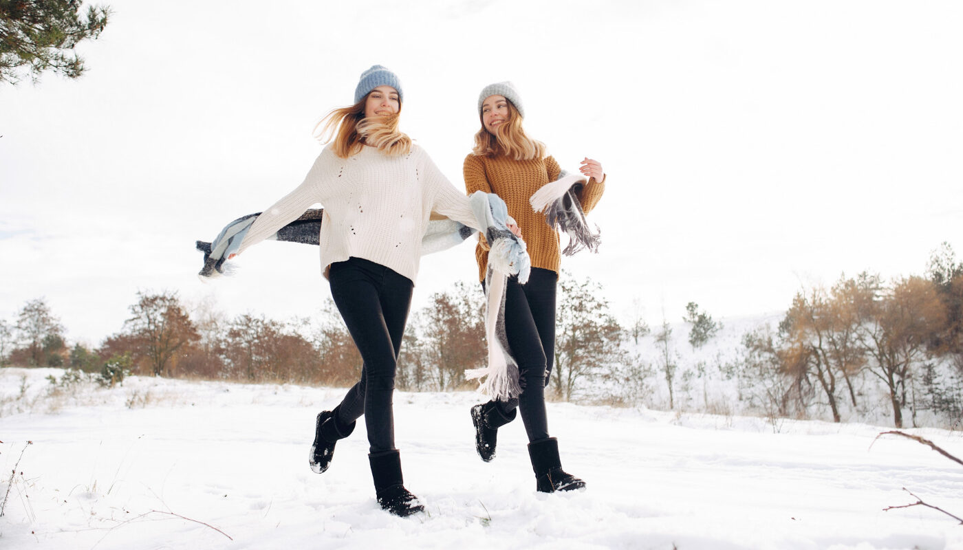 Две девушки греют ноги на зимней прогулке