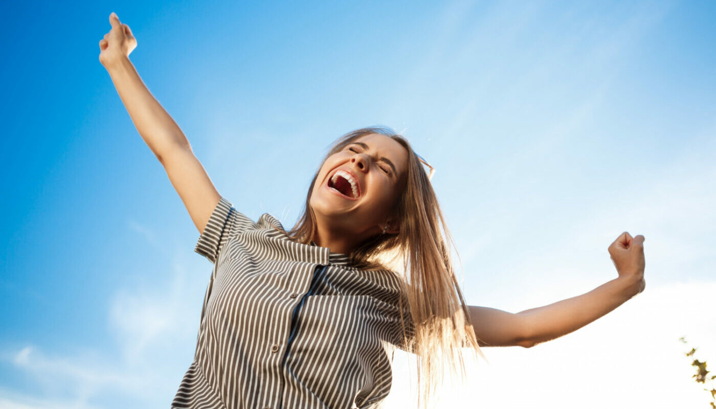 Девушка полная счастья на фоне неба.