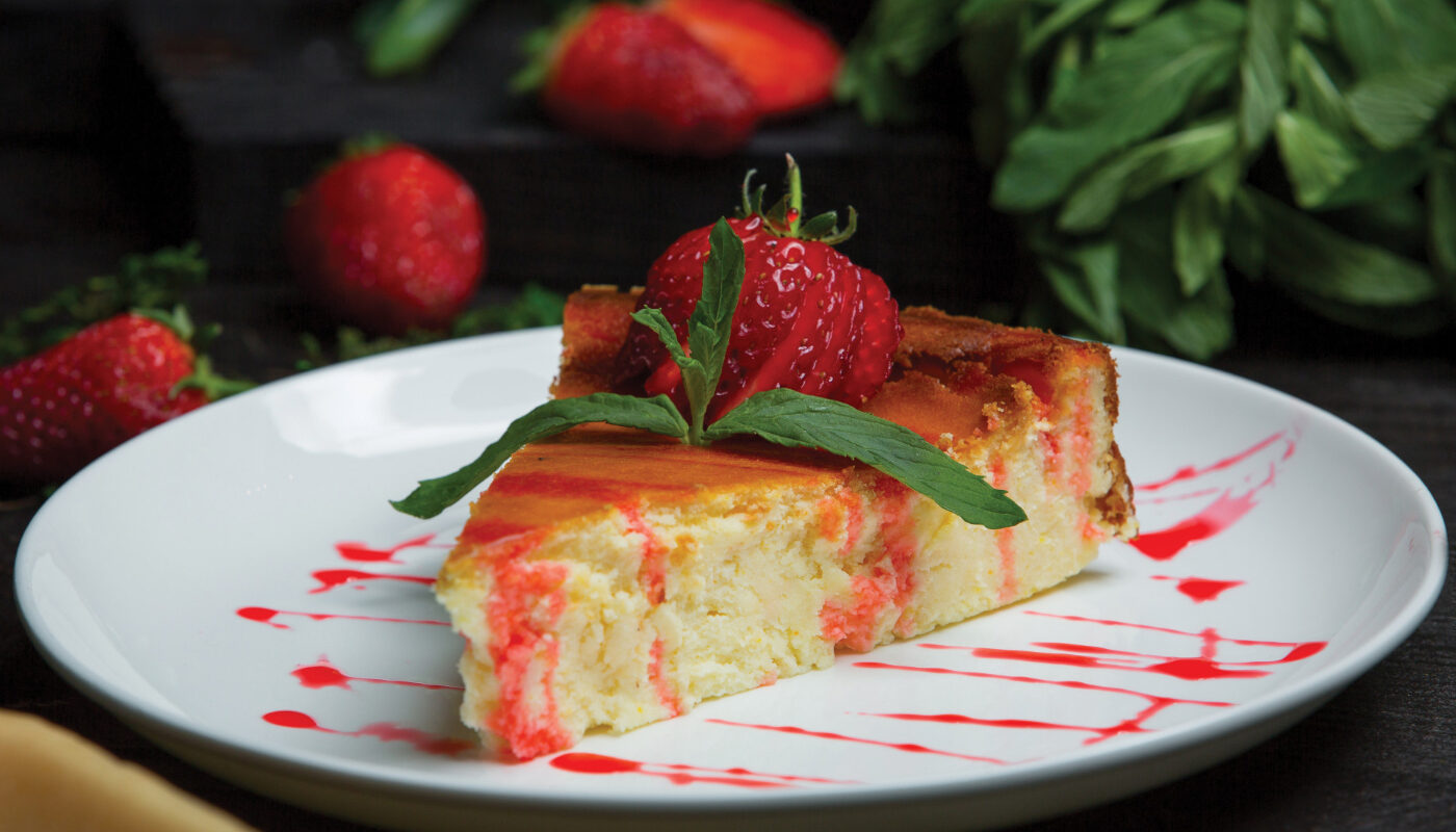 Творожная запеканка украшенная ягодой клубники на тарелке