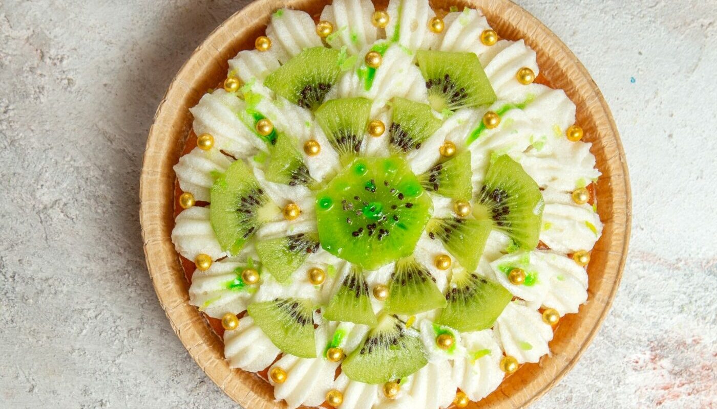 vid-sverhu-vkusnyi-desert-kivi-s-konfetami-na-svetlom-belom-fone-desertnyi-tort-krem-fruktovyi-tropiceskii