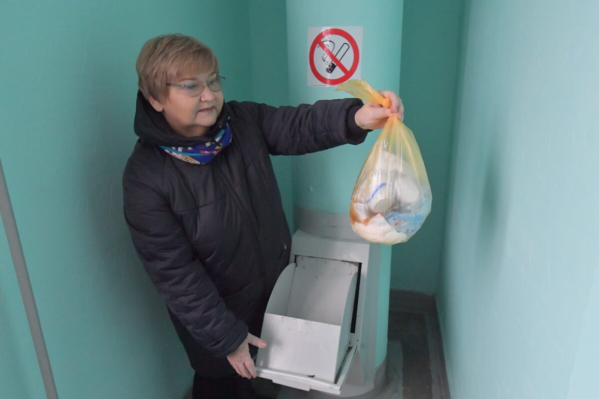 женщина выбрасывает мусор в мусоропровод